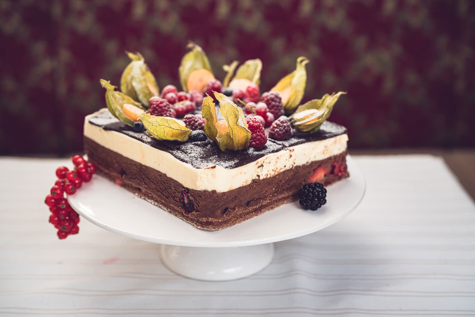 Torte auf einem Tablett auf Tisch mit Früchten dekoriert und serviert