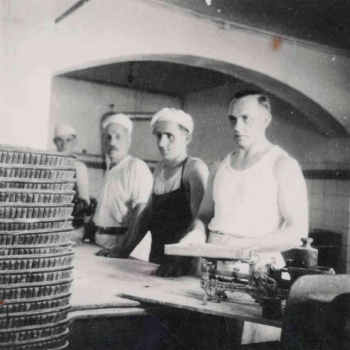 Historisches Bild von vier Bäckern in einer Backstube, schwarz weiß