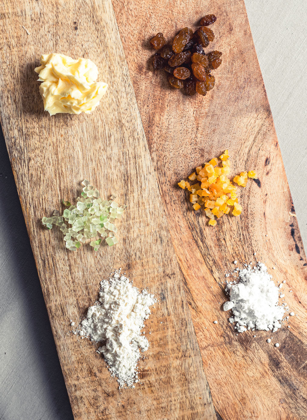 Zuaten Butter, Rosinen, Zucker, Mehl und mehr auf einem Schneidebrett in der Top-Down Perspektive