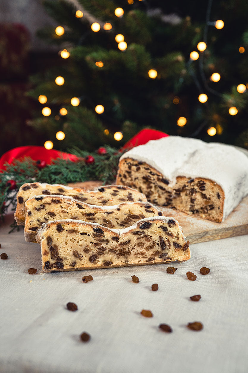 Dresdner Christstollen mit Rosinen, aufgeschnitten aufgereiht vor weihnachtlicher Dekoration